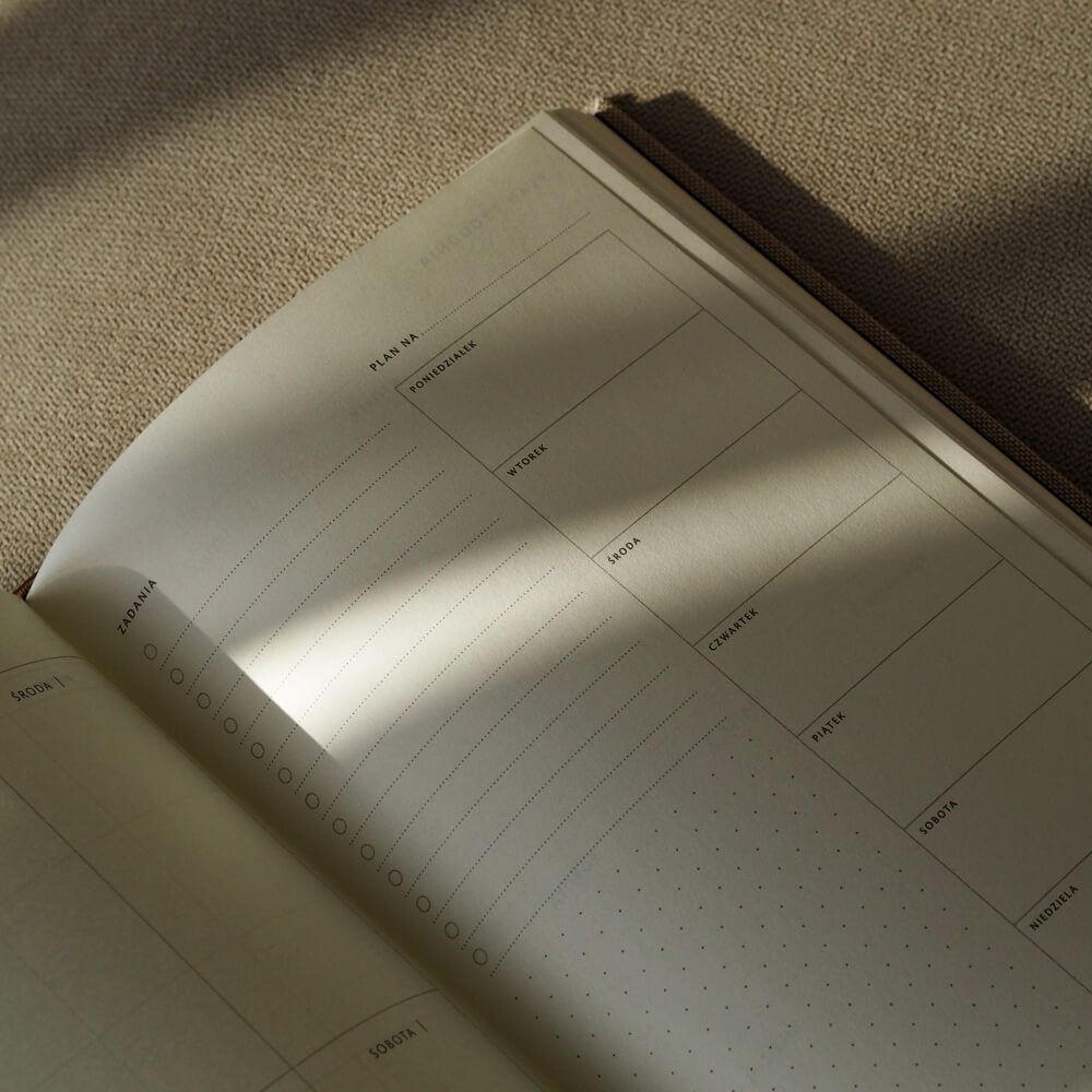 Otwarty lniany planer tygodniowy z miejscem na notatki i listę zadań obok kalendarza tygodniowego.