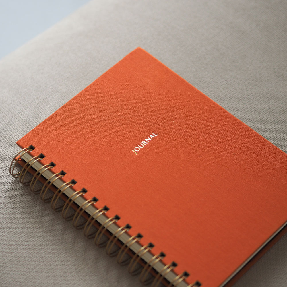 Pomarańczowy planer tygodniowy na spirali – elegancki układ, twarda okładka, nowoczesna forma.